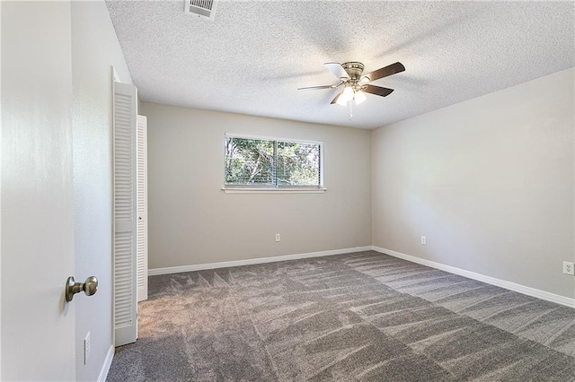 unfurnished bedroom with ceiling fan, dark carpet, a textured ceiling, and a closet