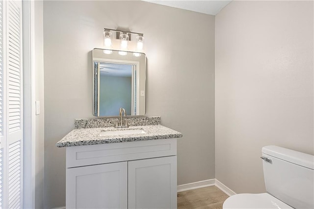 bathroom with hardwood / wood-style flooring, vanity, and toilet