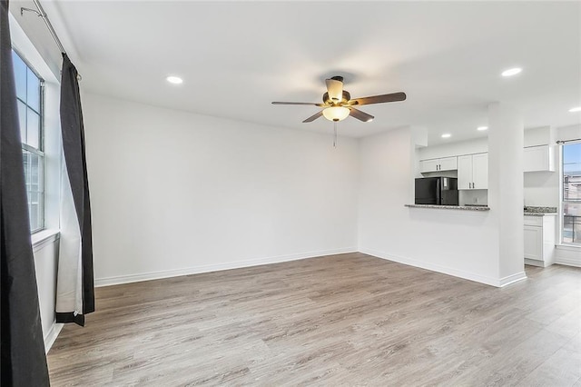 unfurnished living room featuring ceiling fan and light wood-type flooring