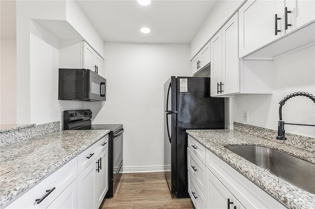 kitchen with light stone countertops, white cabinetry, sink, and black appliances