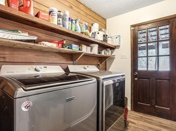 laundry room with a textured ceiling, light hardwood / wood-style flooring, and washer and clothes dryer