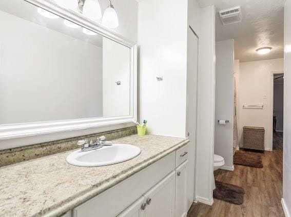 bathroom with toilet, vanity, and hardwood / wood-style flooring