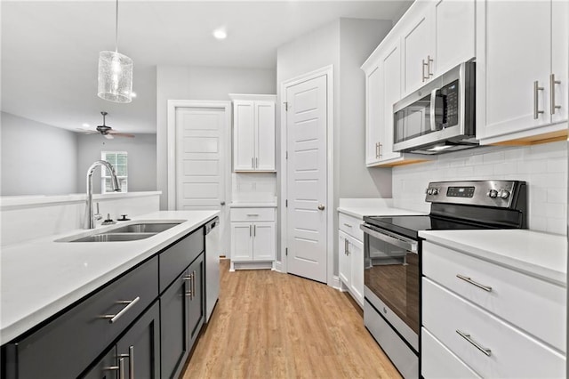 kitchen featuring pendant lighting, sink, ceiling fan, white cabinetry, and stainless steel appliances