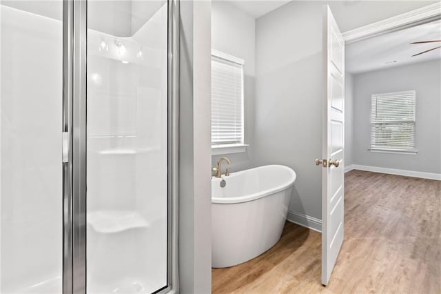 bathroom with hardwood / wood-style flooring, separate shower and tub, and ceiling fan