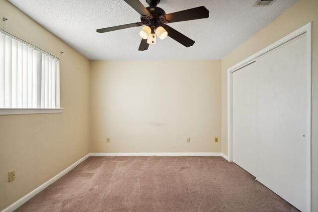 unfurnished bedroom featuring carpet, a textured ceiling, a closet, and ceiling fan