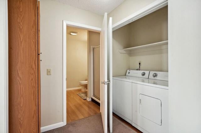 laundry area with hardwood / wood-style floors, a textured ceiling, and separate washer and dryer