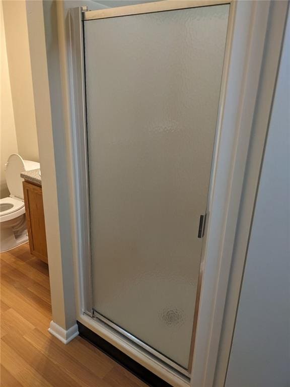 bathroom featuring hardwood / wood-style floors, vanity, toilet, and an enclosed shower