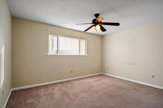 carpeted empty room with ceiling fan and a textured ceiling