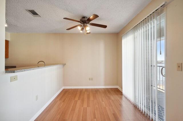 spare room with ceiling fan, light hardwood / wood-style flooring, and a textured ceiling