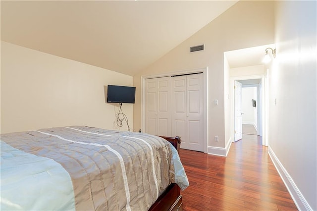 bedroom featuring hardwood / wood-style floors, high vaulted ceiling, and a closet