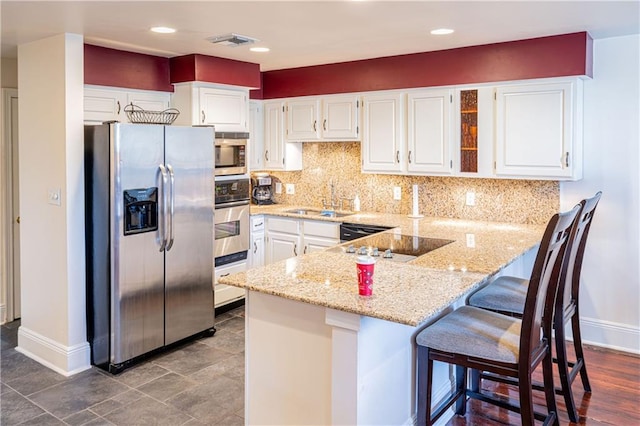 kitchen featuring a breakfast bar, white cabinets, sink, appliances with stainless steel finishes, and kitchen peninsula