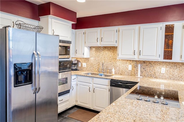 kitchen with decorative backsplash, white cabinetry, sink, and stainless steel appliances