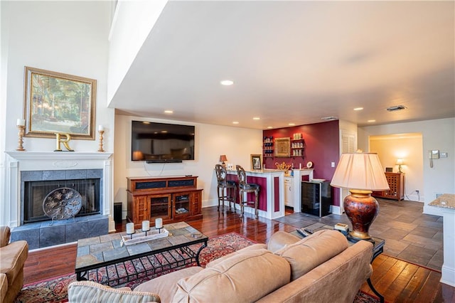 living room featuring bar, a tiled fireplace, and wood-type flooring