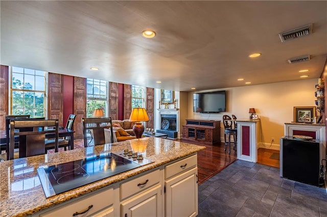 kitchen with light stone countertops, black electric stovetop, and white cabinetry