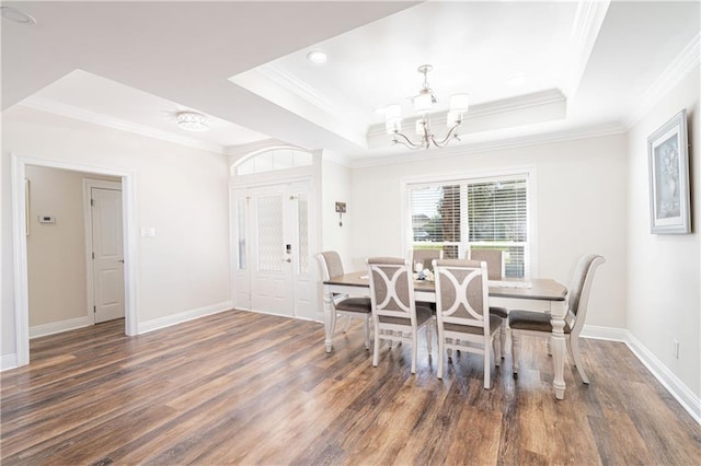 dining area with a tray ceiling, crown molding, and dark wood-type flooring