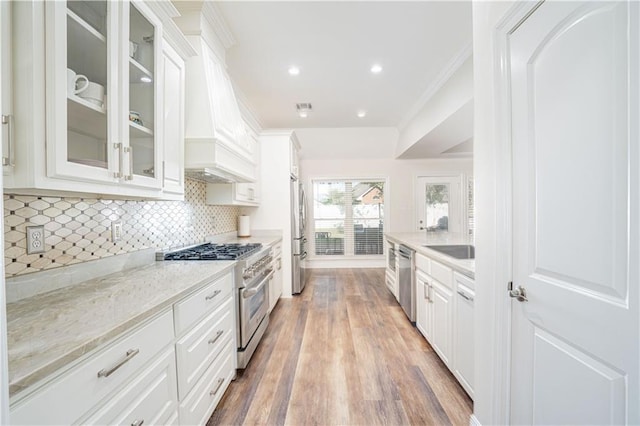 kitchen with dark hardwood / wood-style flooring, stainless steel appliances, white cabinetry, and light stone counters