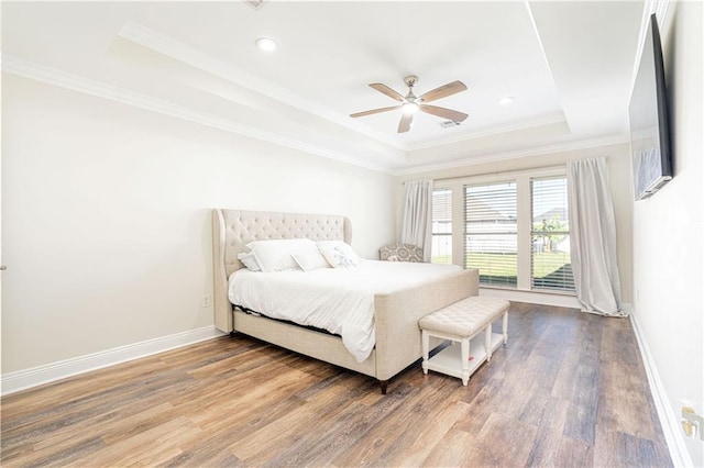 bedroom with hardwood / wood-style floors, a raised ceiling, ceiling fan, and crown molding