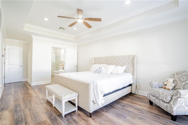 bedroom featuring dark hardwood / wood-style flooring, ensuite bathroom, a tray ceiling, ceiling fan, and crown molding