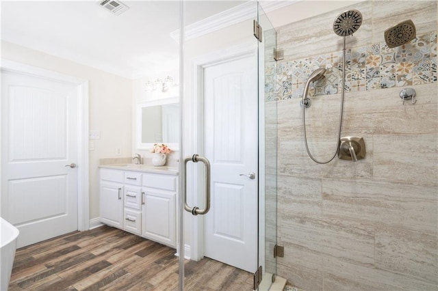 bathroom featuring hardwood / wood-style floors, vanity, a shower with door, and crown molding