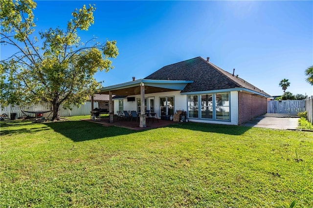 back of house with a patio area and a lawn