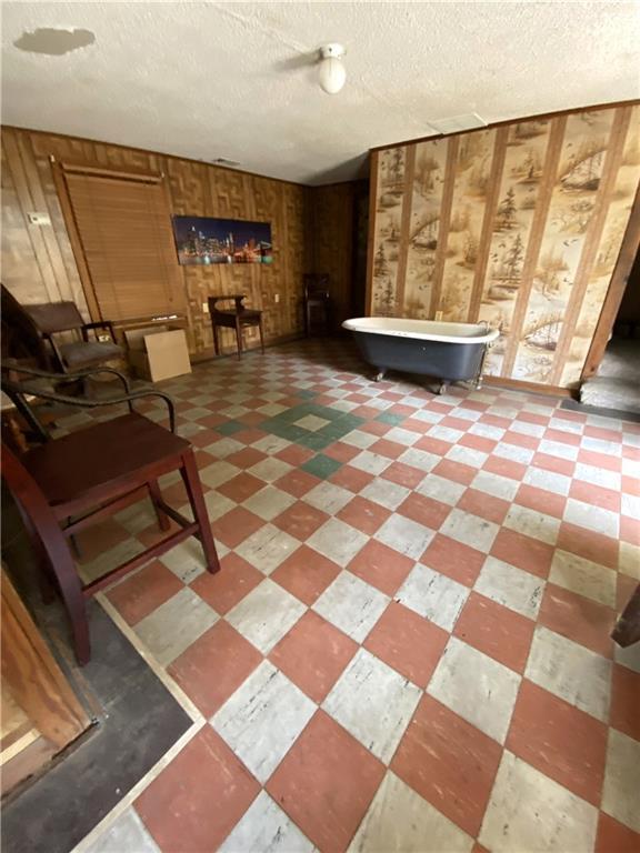 interior space featuring a textured ceiling and wood walls