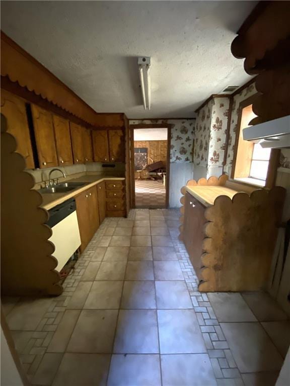 kitchen featuring light tile patterned flooring, a textured ceiling, white dishwasher, and sink