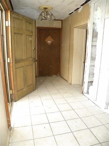 hall with light tile patterned floors and wooden walls