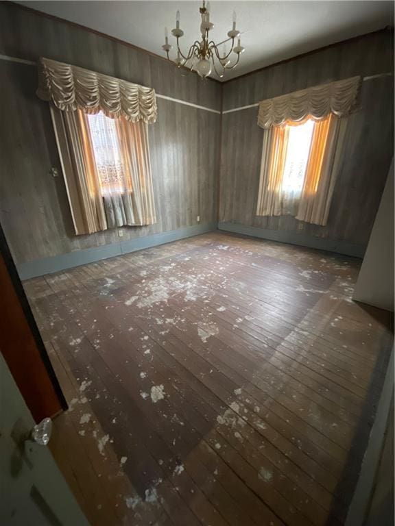 unfurnished dining area featuring a chandelier and hardwood / wood-style floors