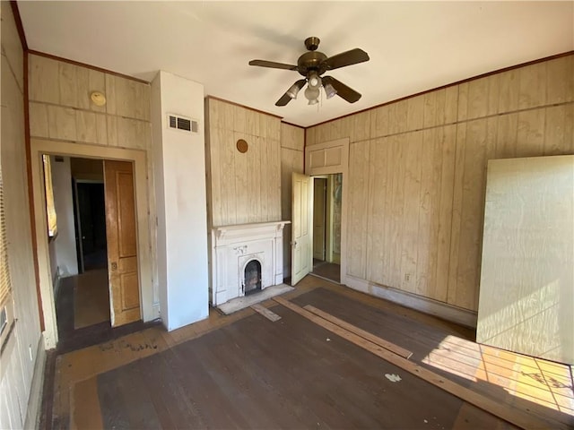 unfurnished living room featuring wooden walls, ceiling fan, and dark wood-type flooring