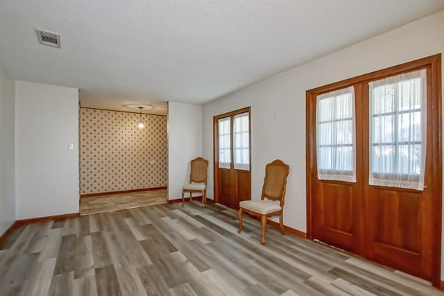 unfurnished room featuring light hardwood / wood-style flooring and a textured ceiling