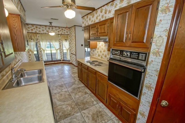 kitchen with pendant lighting, white cooktop, sink, light tile patterned floors, and black oven