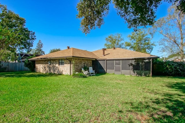 rear view of property featuring a sunroom and a lawn