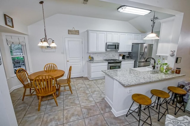 kitchen with sink, white cabinets, vaulted ceiling, and appliances with stainless steel finishes