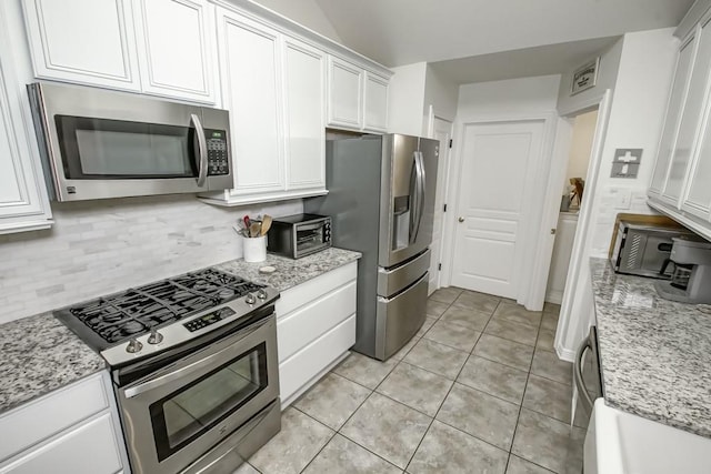 kitchen with light stone countertops, stainless steel appliances, and white cabinetry