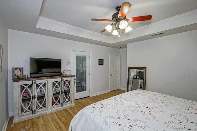 bedroom featuring wood-type flooring, a raised ceiling, ceiling fan, and ornamental molding