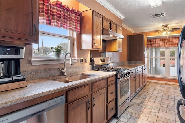 kitchen featuring appliances with stainless steel finishes, ornamental molding, a textured ceiling, ceiling fan, and sink