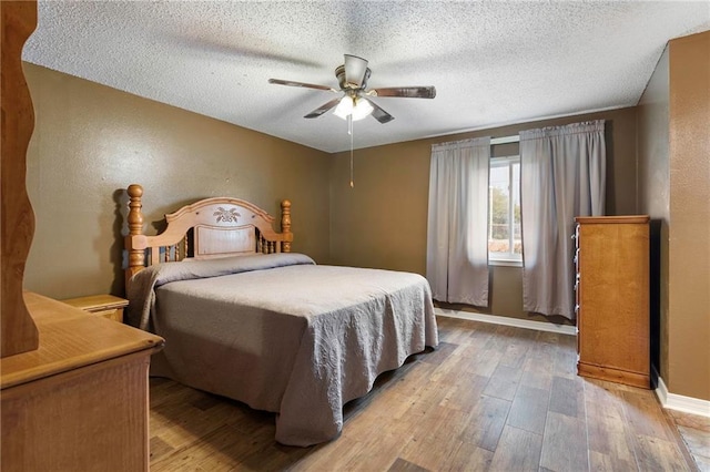 bedroom with a textured ceiling, light hardwood / wood-style flooring, and ceiling fan