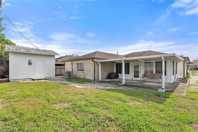 back of property featuring central air condition unit, a patio area, a yard, and a storage unit