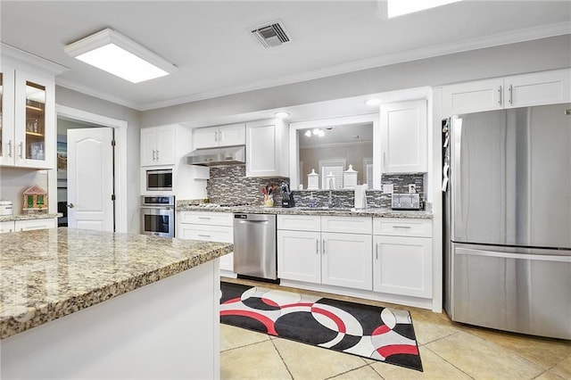 kitchen featuring white cabinetry, stainless steel appliances, light stone counters, ornamental molding, and decorative backsplash