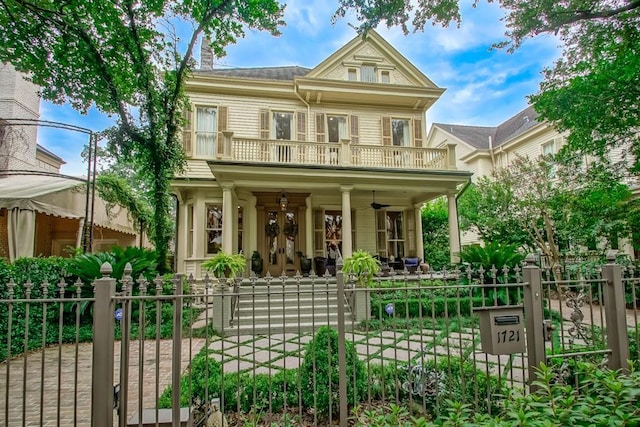 view of front of home featuring a fenced front yard, a gate, a porch, a balcony, and ceiling fan