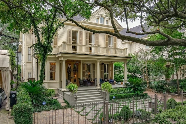 back of property featuring covered porch and a balcony