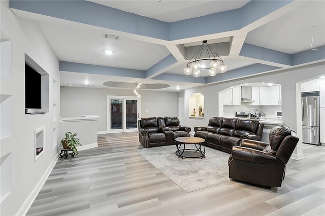 living room with light hardwood / wood-style floors and a notable chandelier