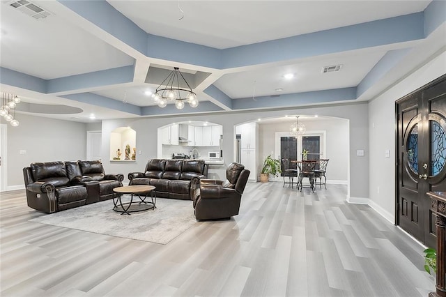 living room with light wood-type flooring and a notable chandelier