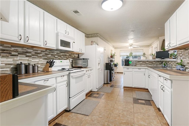 kitchen with white appliances, kitchen peninsula, decorative backsplash, a textured ceiling, and white cabinetry