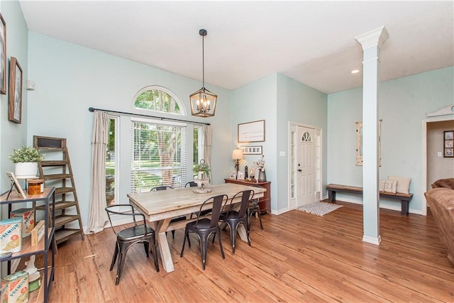 dining area featuring light hardwood / wood-style flooring, a notable chandelier, and ornate columns