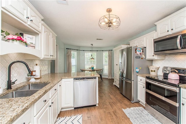 kitchen with white cabinetry, sink, hanging light fixtures, stainless steel appliances, and kitchen peninsula