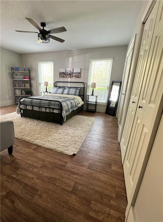 bedroom with a textured ceiling, dark hardwood / wood-style flooring, a closet, and ceiling fan