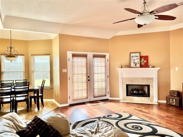 living room featuring french doors, light wood-type flooring, ceiling fan, and ornamental molding