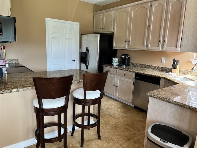 kitchen featuring a kitchen breakfast bar, sink, light tile patterned floors, appliances with stainless steel finishes, and light stone counters