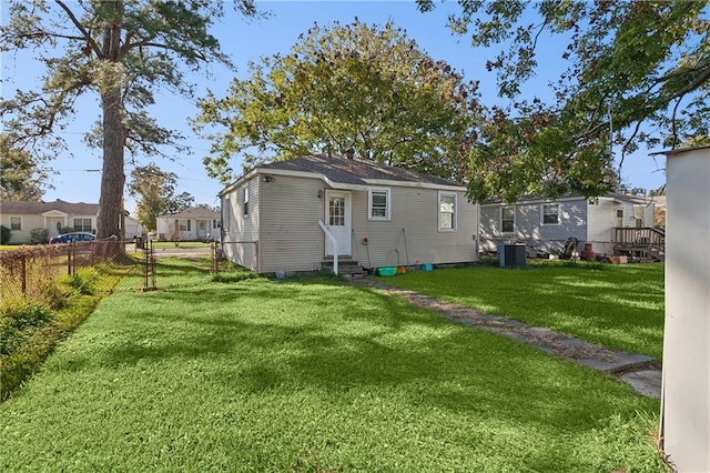 rear view of house featuring central AC and a lawn